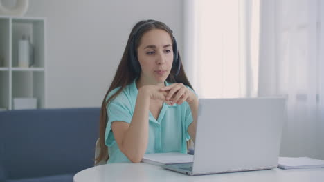 Female-Operator-In-Call-Center-Work.-Young-business-woman-wearing-headphones-communicating-by-video-call.-businesswoman-speaking-looking-at-laptop-computer-online-conference-distance-office-chat